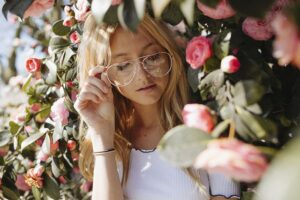 blonde woman wearing glasses surrounded by flowers